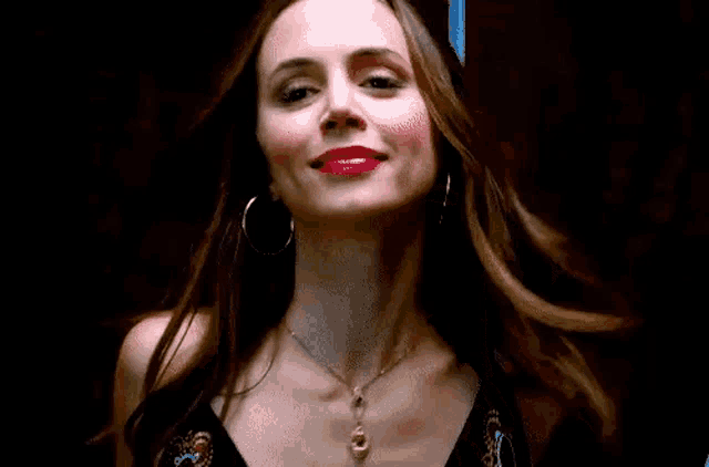 a woman wearing red lipstick and hoop earrings is smiling .