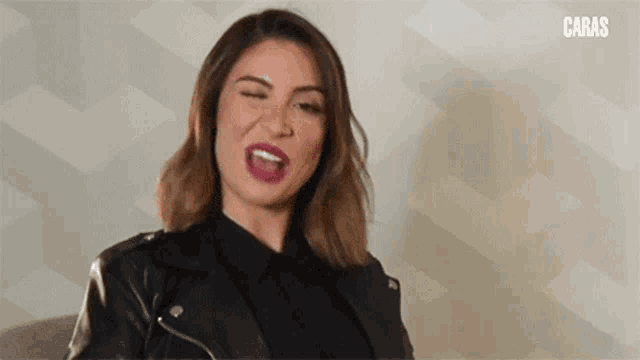 a woman wearing a leather jacket is making a funny face .