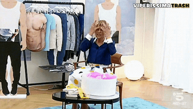 a woman is sitting at a table with a cake and a sign that says viperissima trash above her