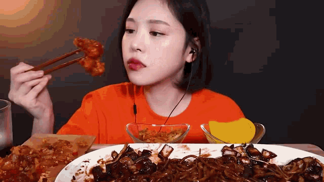 a woman is eating food with chopsticks and a plate of food .