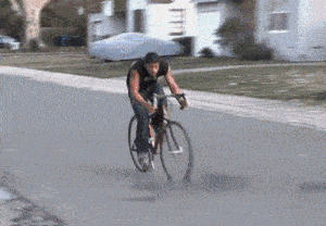 a man is riding a bike down a street in front of a house