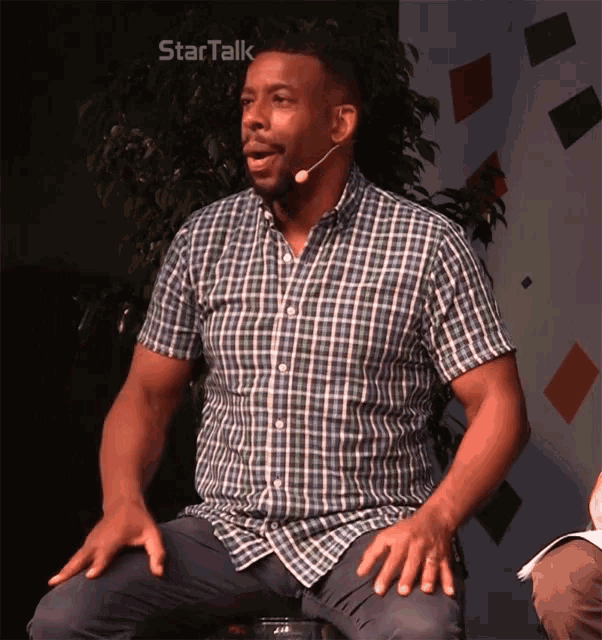 a man in a plaid shirt is sitting in front of a startalk logo