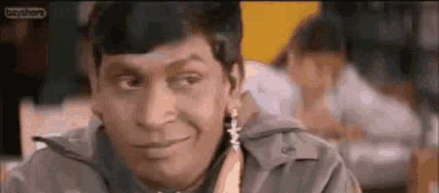 a man in a trench coat is making a funny face while sitting in a restaurant .