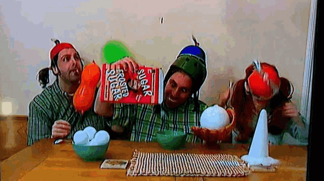 a group of people are sitting at a table with a box of sugar snaps in front of them
