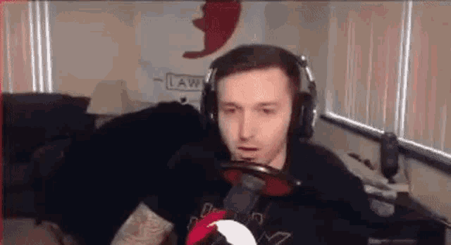 a man wearing headphones is sitting in front of a microphone and holding a steering wheel .