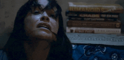 a woman is laying on a bed next to a pile of books .