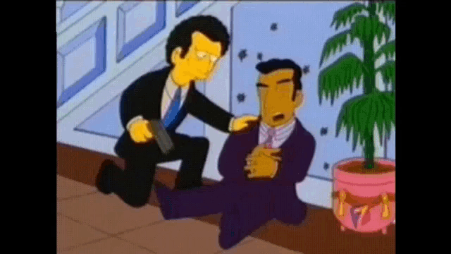 a man in a suit and tie is kneeling down next to another man with a gun