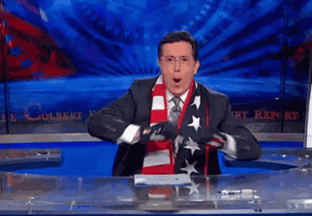 a man in a suit and tie is holding an american flag around his neck