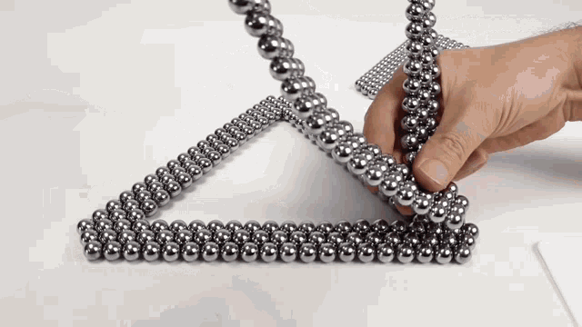 a hand is holding a string of metal beads
