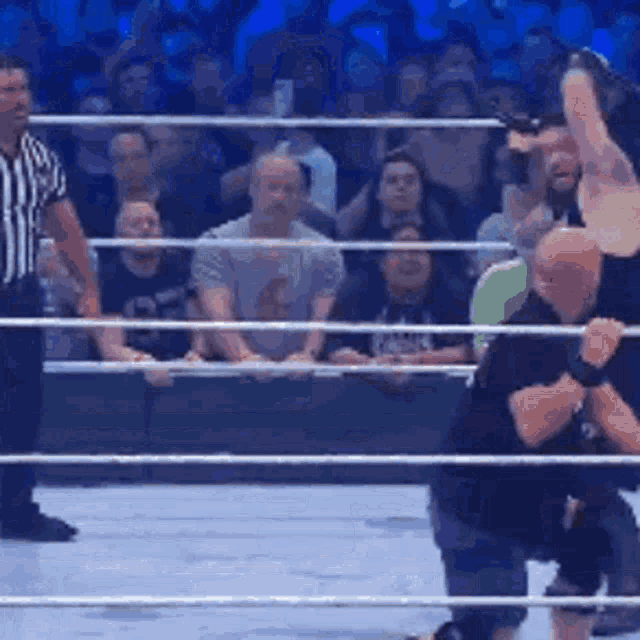 a man is being lifted in the air in a wrestling ring while a referee watches .