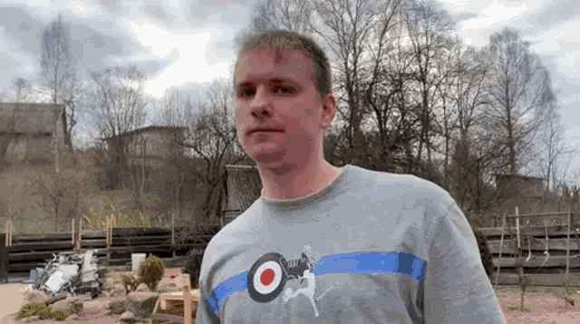 a man wearing a grey shirt with a target on it looks at the camera