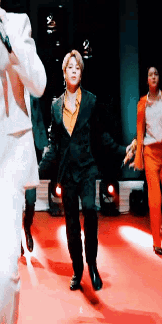a man in a suit is dancing on a red carpet while holding a microphone