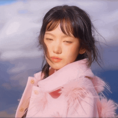 a woman wearing a pink coat with feathers on the hood
