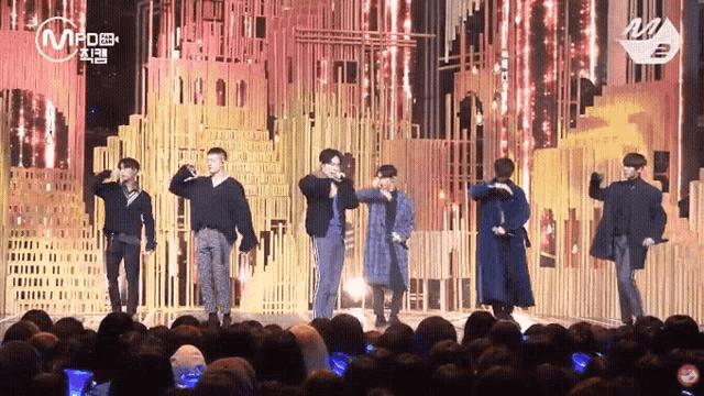 a group of men are standing on a stage in front of a crowd with a sign that says m.po