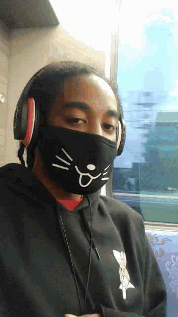 a person wearing headphones and a cat mask