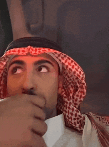 a man wearing a head scarf is covering his mouth