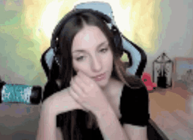 a woman wearing headphones is sitting in a chair with her hand on her chin