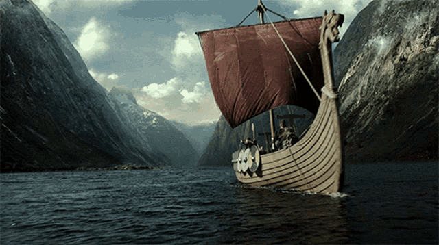 a boat with a red sail is in the middle of a river