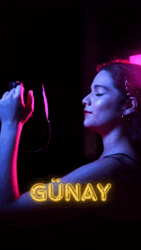 a woman is looking at herself in a mirror with the name günay on the bottom right