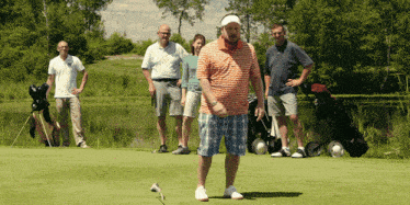a group of golfers are standing on a green with a man holding a golf club