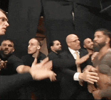 a group of men are standing next to each other in a dark room and talking .