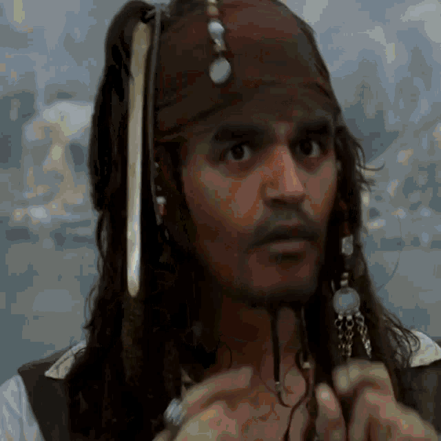a man with dreadlocks and a scarf on his head looks at the camera