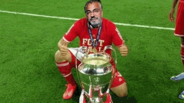 a man in a red shirt is kneeling down holding a trophy .