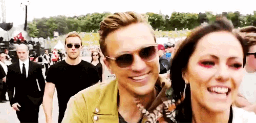 a man and a woman wearing sunglasses are standing next to each other at a festival .