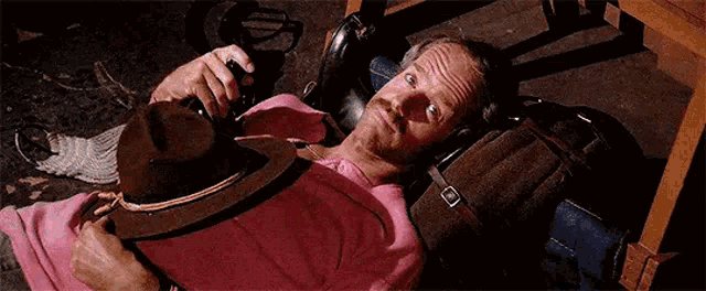 a man is laying on the floor laughing while holding a hat .