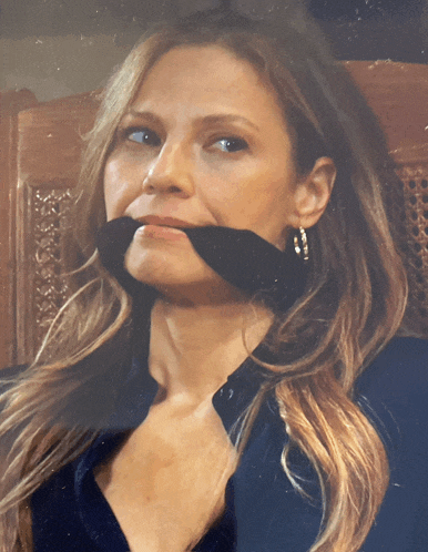 a woman with a black bandage around her mouth looks at the camera