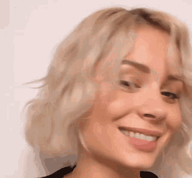 a close up of a woman 's face with blonde hair smiling