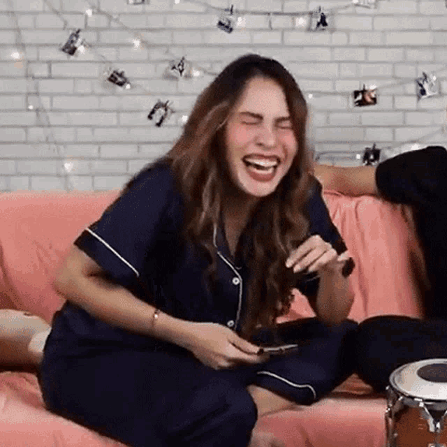 a woman is laughing while sitting on a couch next to a drum .