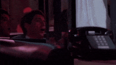 a man with a ring on his finger is smoking a cigar in a dark room .