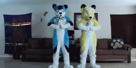 two furry costumes are standing next to each other in a living room with a couch .
