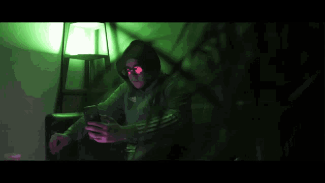 a man wearing a hoodie and sunglasses is looking at his cell phone