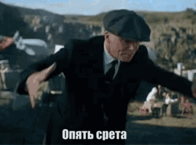 a man in a suit and hat is dancing in a field with his arms outstretched .