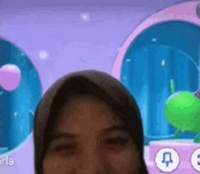a woman wearing a hijab is looking at the camera in front of a screen with balloons in the background .