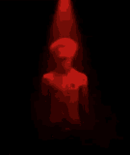a statue of a man is standing in a dark room under a red light .