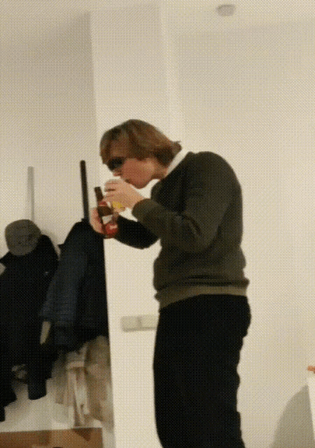 a man in a green sweater is drinking from a red cup