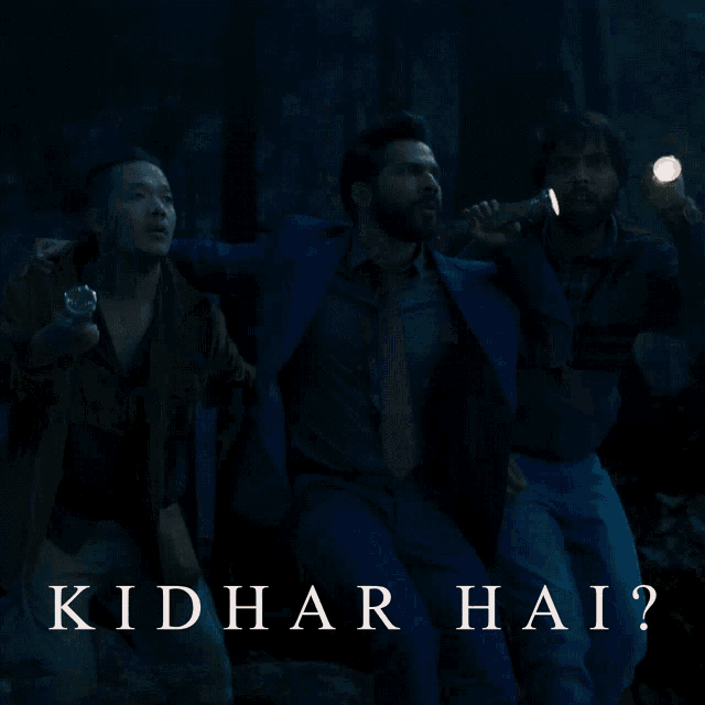 a man holding a flashlight in a dark room with the words kidhar hai on the bottom