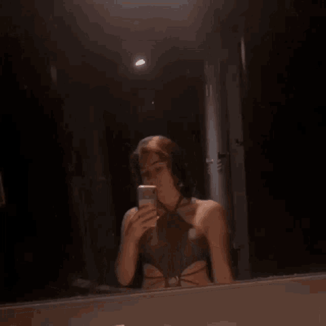 a woman taking a picture of herself in a mirror with her phone