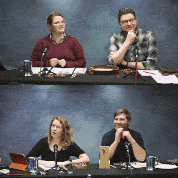 a man and a woman are sitting at a table with microphones in front of them