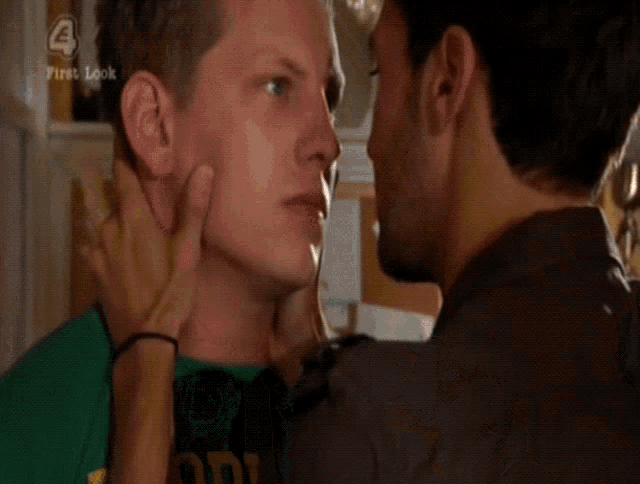 two men are kissing in a room with a first look logo on the bottom right