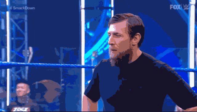 a man in a black shirt is standing in a wrestling ring with the fox logo on the bottom
