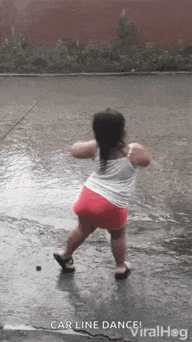 a little girl is dancing in the rain on a wet street .