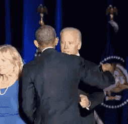 a man in a suit is dancing with a woman in a blue dress behind him .