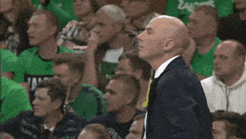 a man in a suit stands in front of a crowd wearing a green shirt that says ' zygmunt '