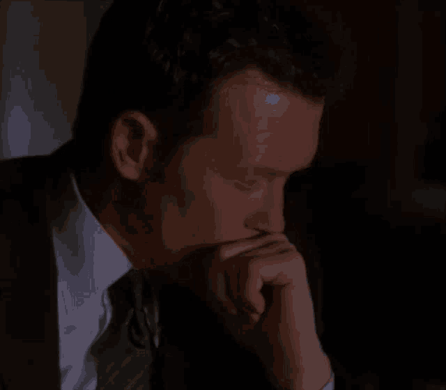 a man in a suit and tie has his hand on his mouth