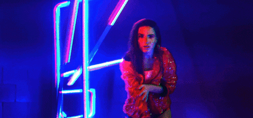 a close up of a woman wearing hoop earrings in a dark room with neon lights .