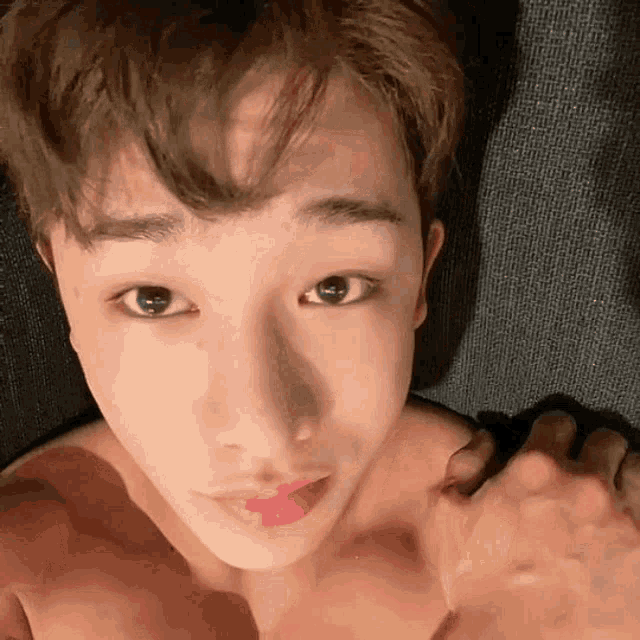 a young man without a shirt is taking a selfie with his hand .